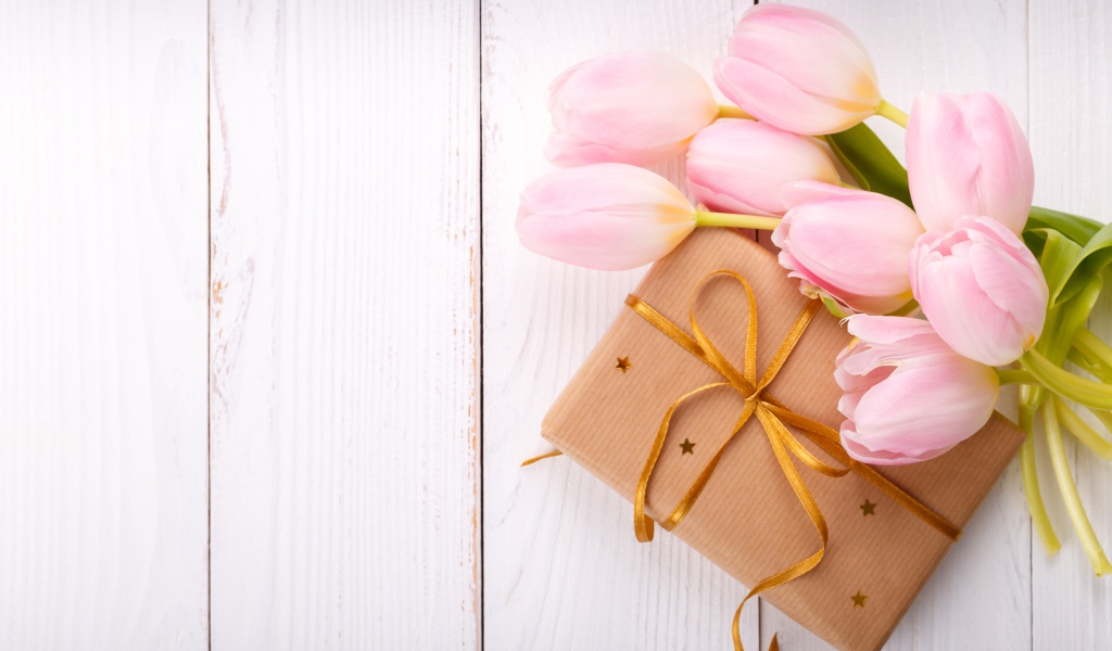 Букет нежных тюльпанов с подарком на деревянном столе