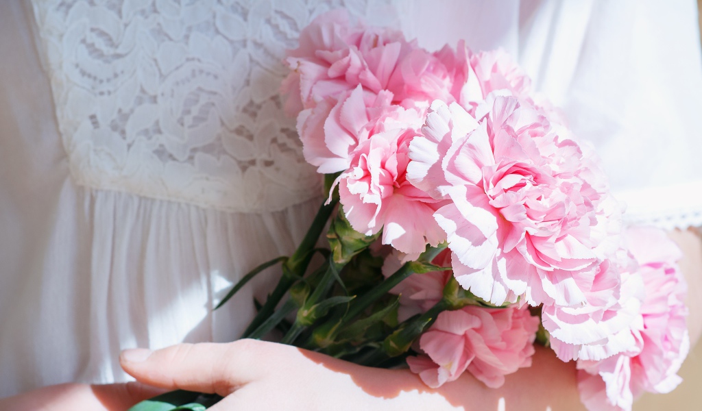 Букет розовых цветов гвоздики в руках у невесты