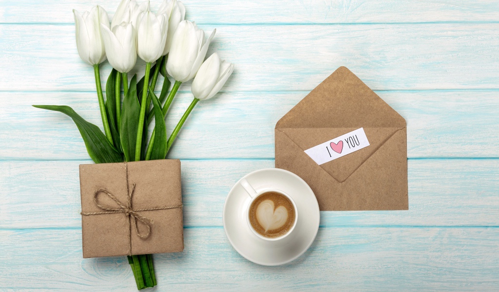 Букет белых тюльпанов на столе с подарком и чашкой кофе