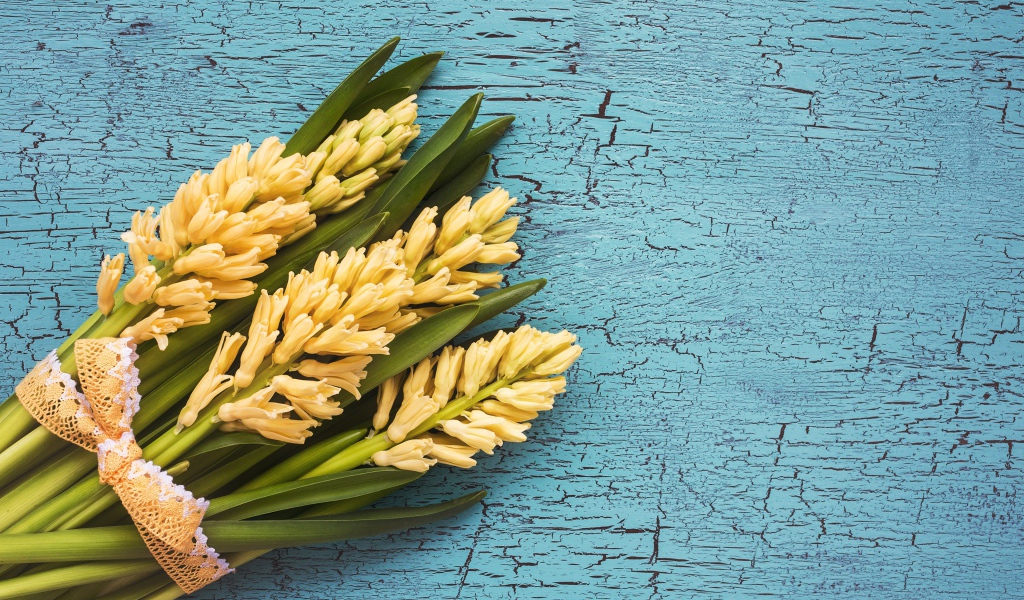 Букет желтых гиацинтов с зелеными листьями на голубом фоне