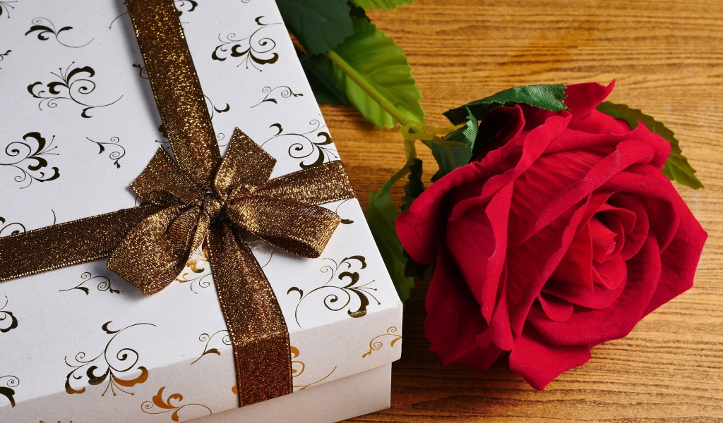 Красный цветок розы на столе с подарком