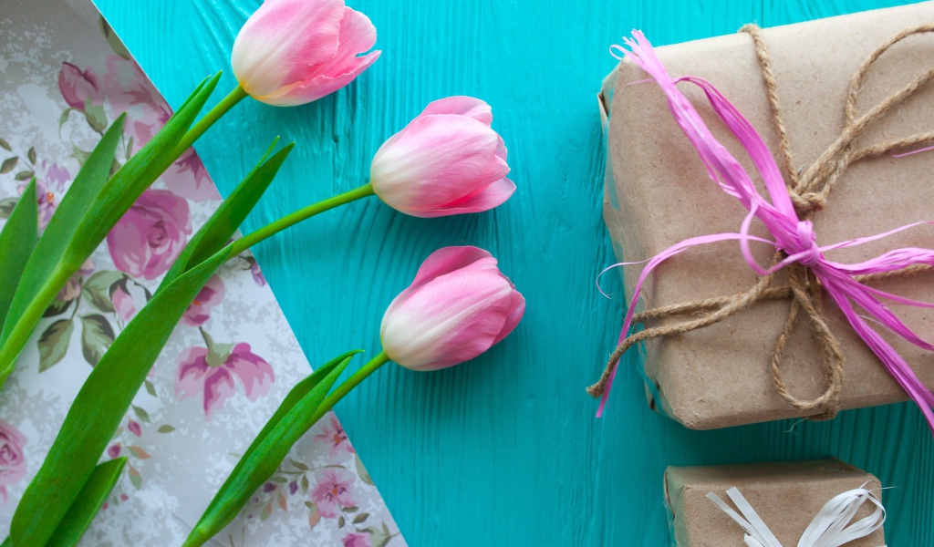 Три розовых тюльпана на голубом столе с подарками