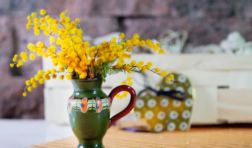 Желтые цветы мимозы в маленькой вазе на столе