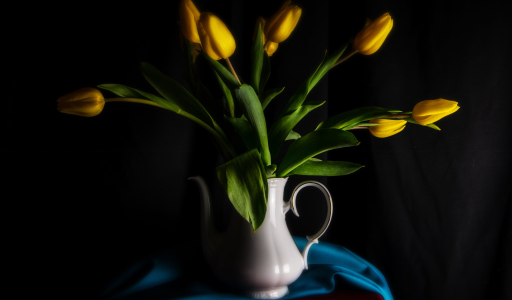 Желтые тюльпаны в белой вазе на черном фоне