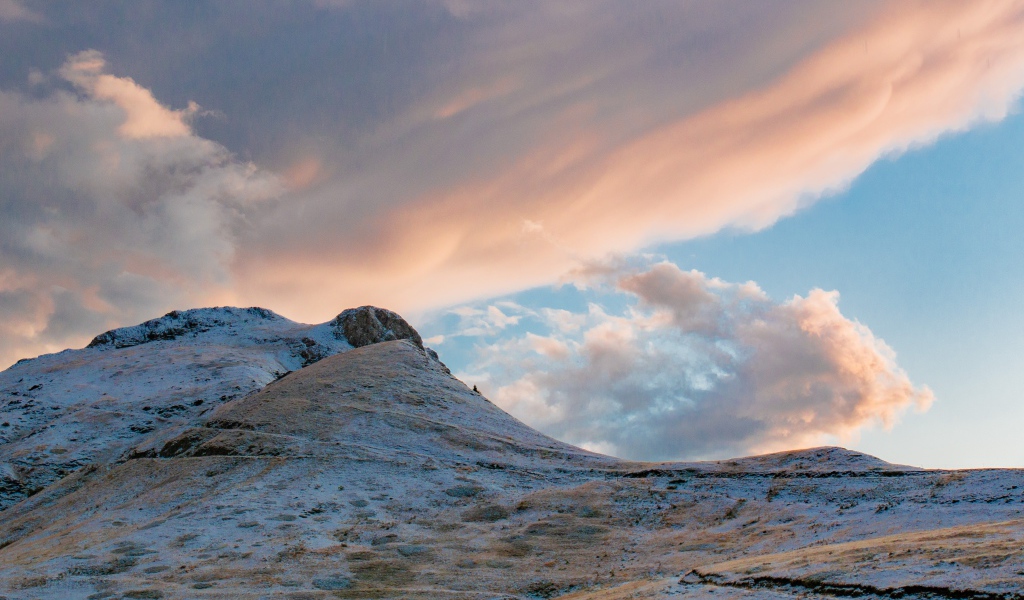 Красивые серые облака над заснеженной горой 