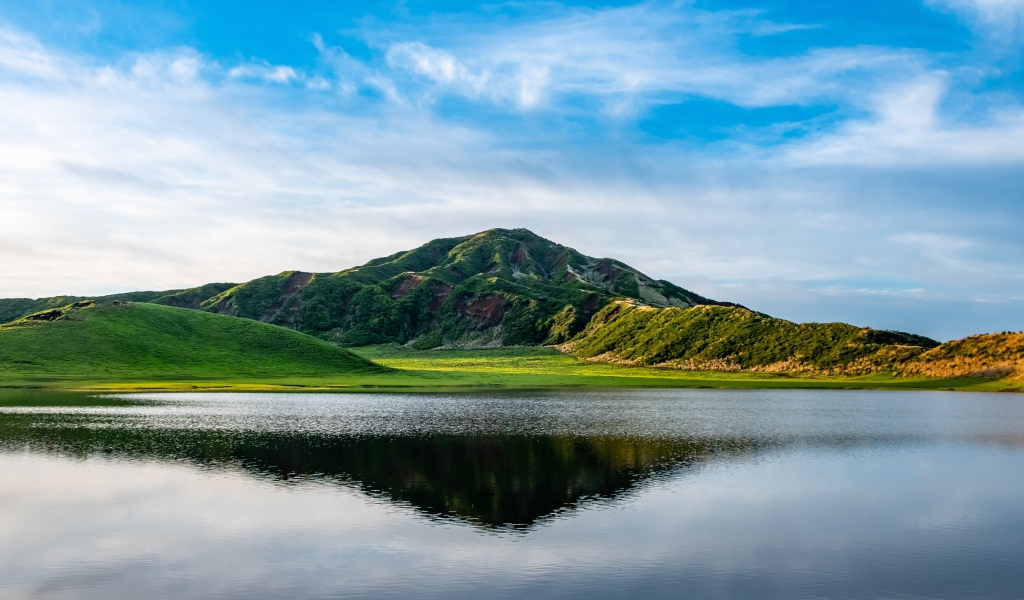 Красивый вид на покрытую зеленью гору под голубым небом у озера
