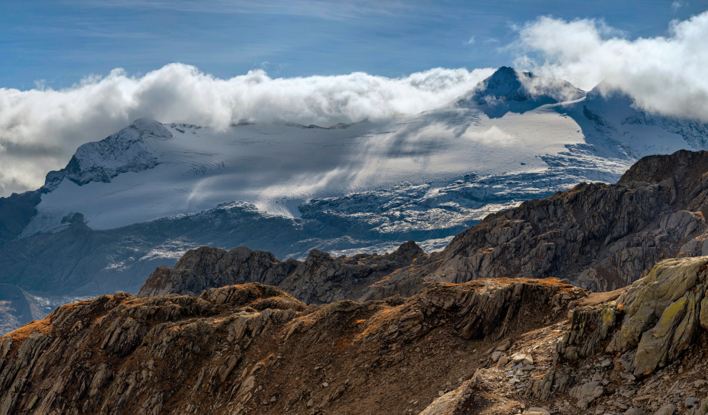 Густые белые облака над заснеженными Альпами