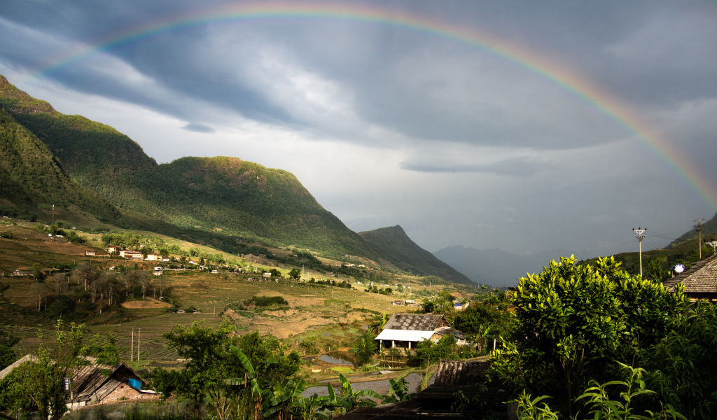 Большая разноцветная радуга в небе над горами