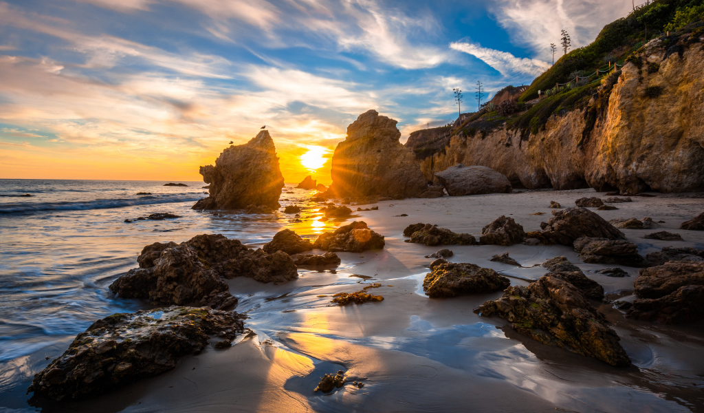 Яркий рассвет летнего солнца над скалами и океана