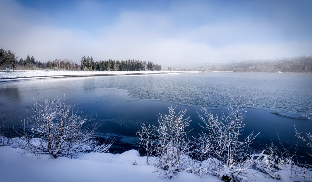 Покрытая льдом река  с заснеженными берегами зимой