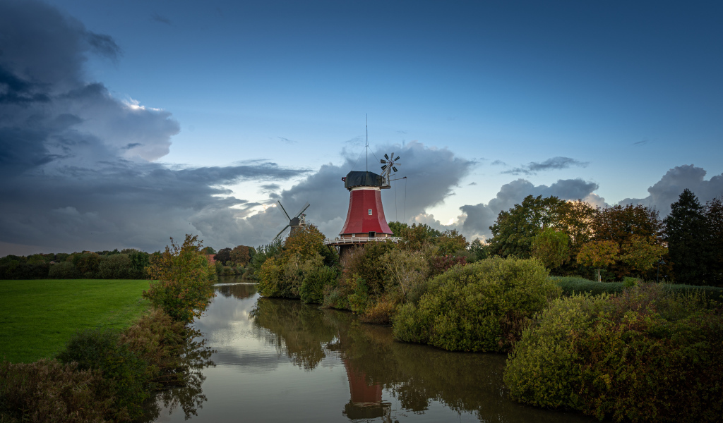 Мельница на берегу реки под красивым небом в сумерках