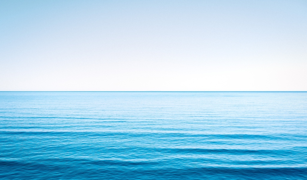 Спокойная голубая морская вода под голубым небом 