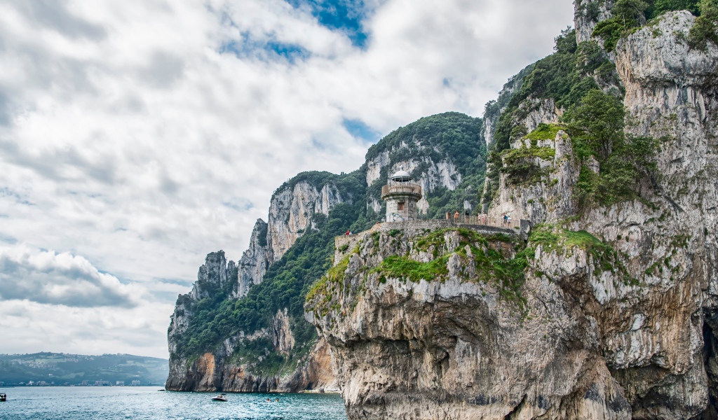 Высокие скалы у моря под белыми облаками 