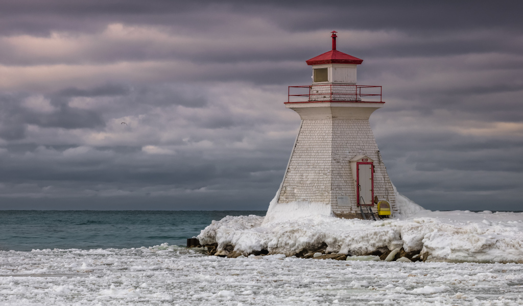 Маяк на покрытом льдом берегу у моря