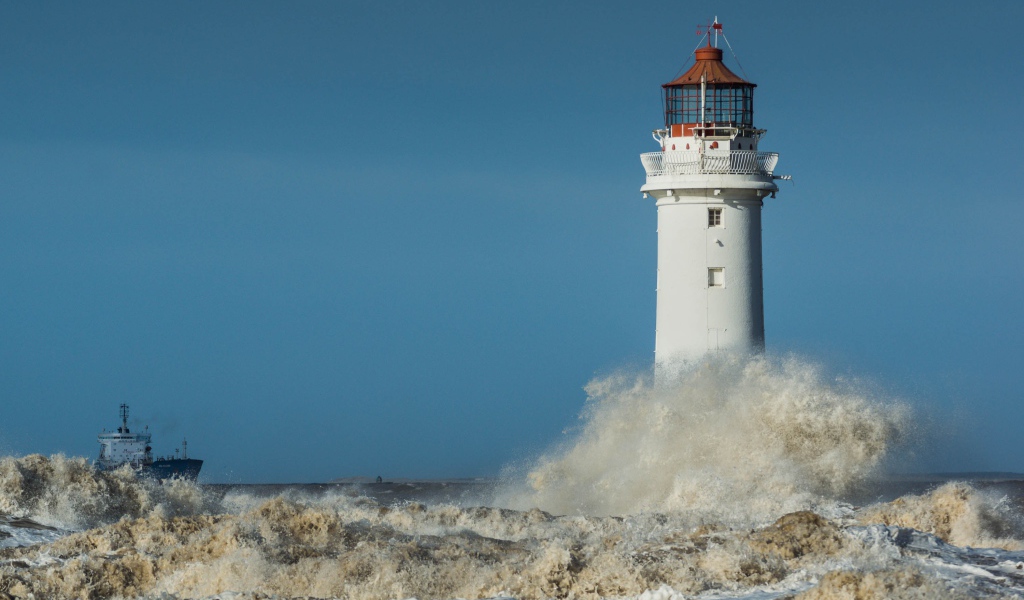 Бушующие белые волны бьются о маяк 