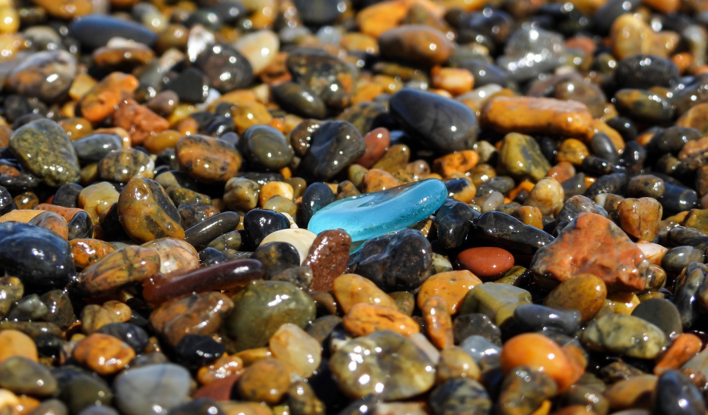 Гладкие разноцветные мелкие камни на пляже 