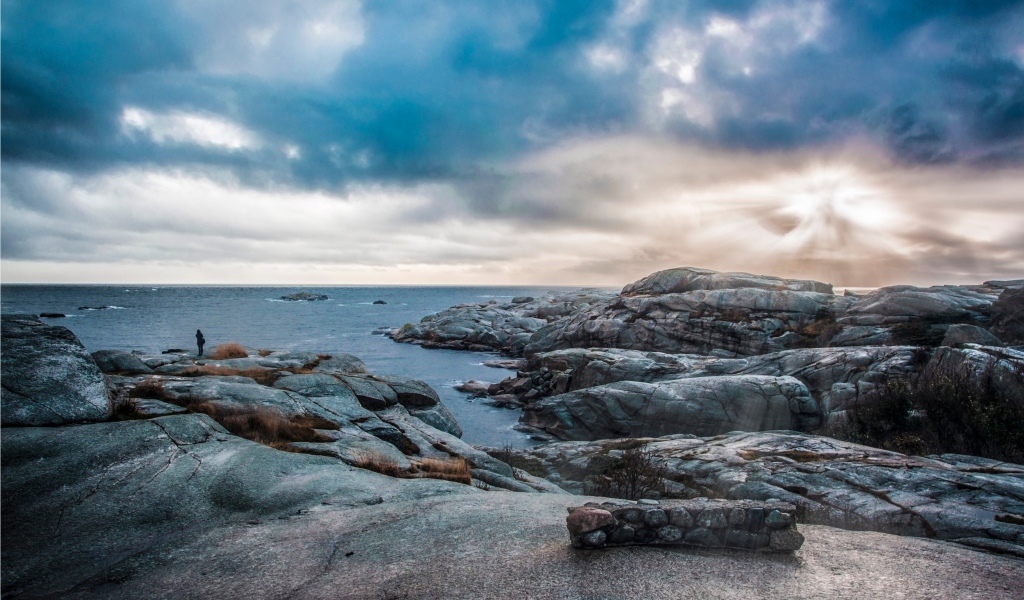 Каменный берег у тихого моря под черными облаками