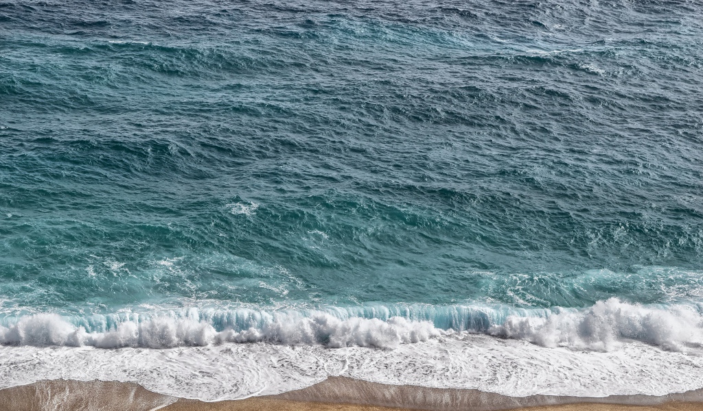 Белая пена от голубой морской воды на песке 