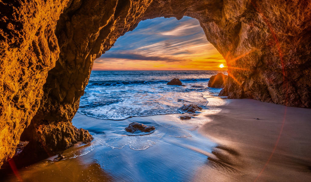 Закат солнца в каменной арке в море