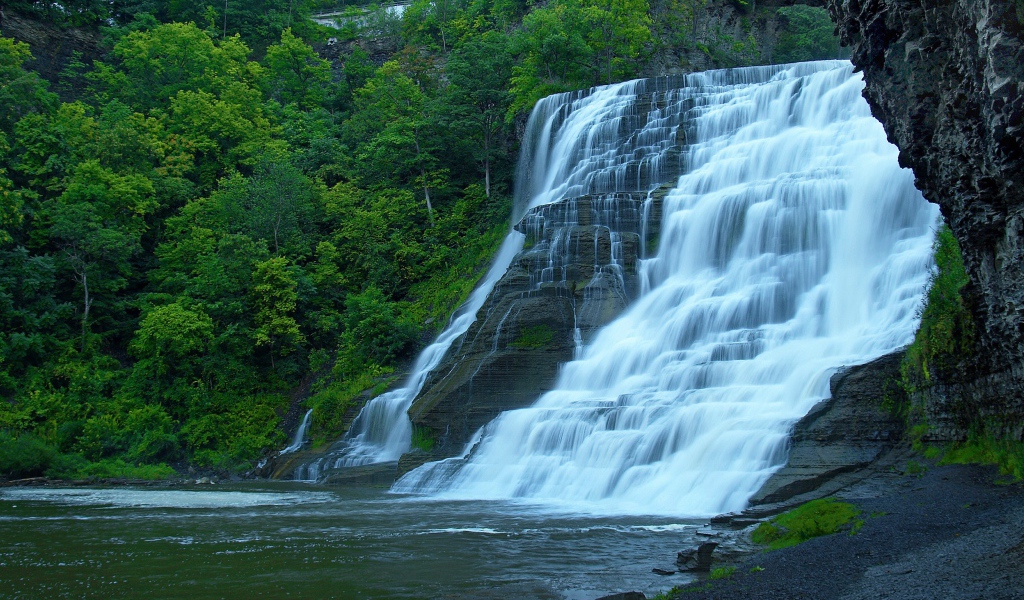 Красивый каскадный водопад с зелеными деревьями