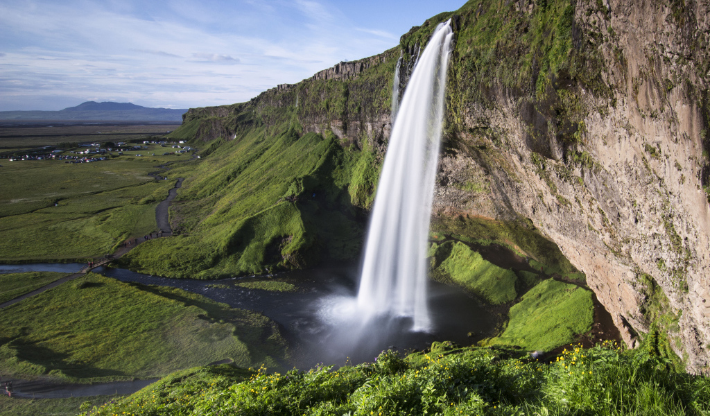 Быстрый водопад Сельяландсфосс стекает со скалы, Исландия