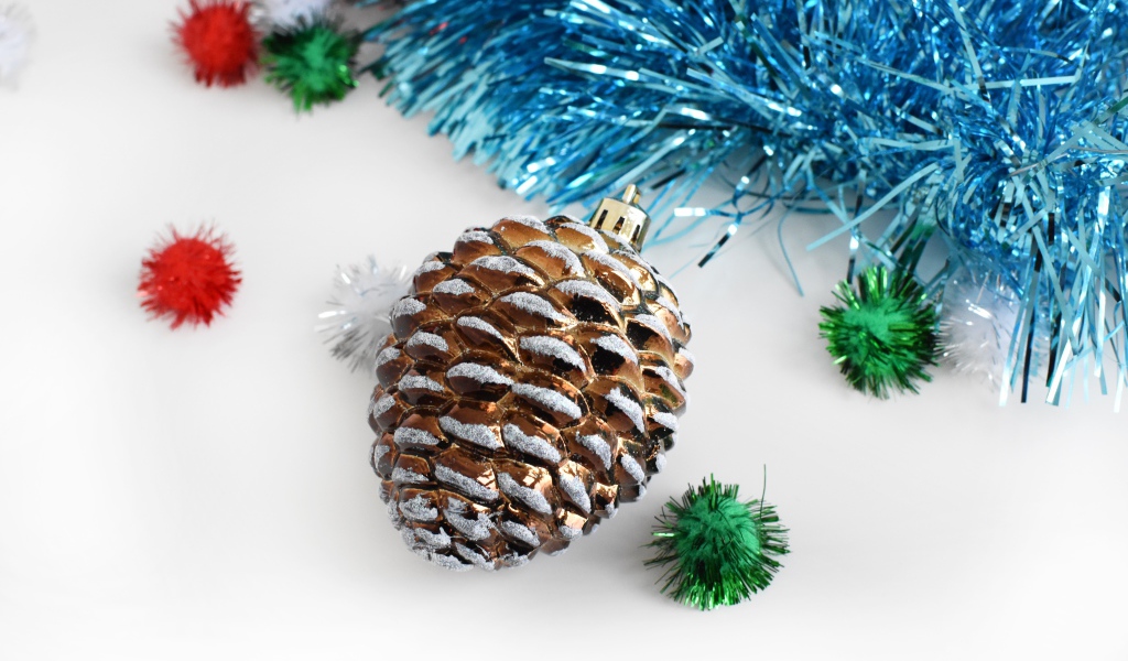 Елочная игрушка шишка с мишурой на белом фоне 