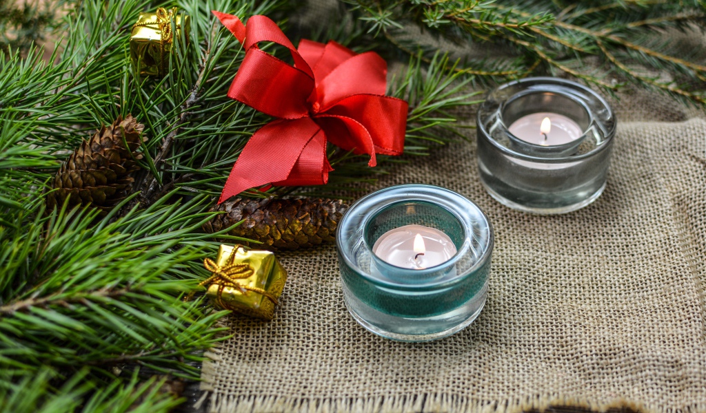 Две зажженные свечи, еловая ветка и красный бант на рождество 