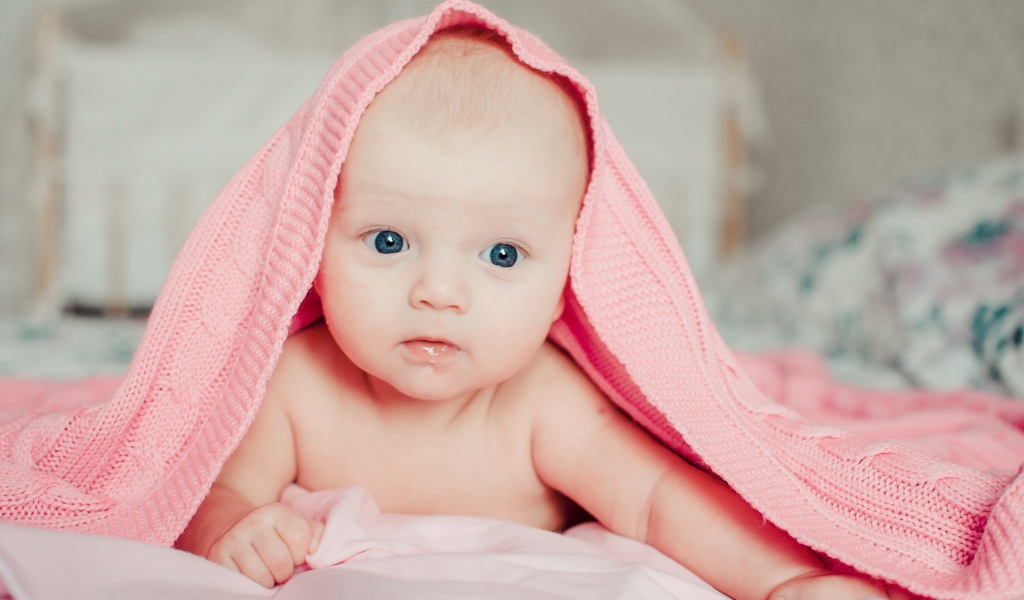 Грудной ребенок лежит под розовым пледом