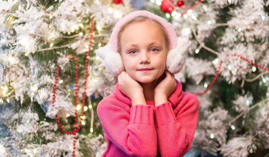 Девочка в розовых наушниках сидит у ели