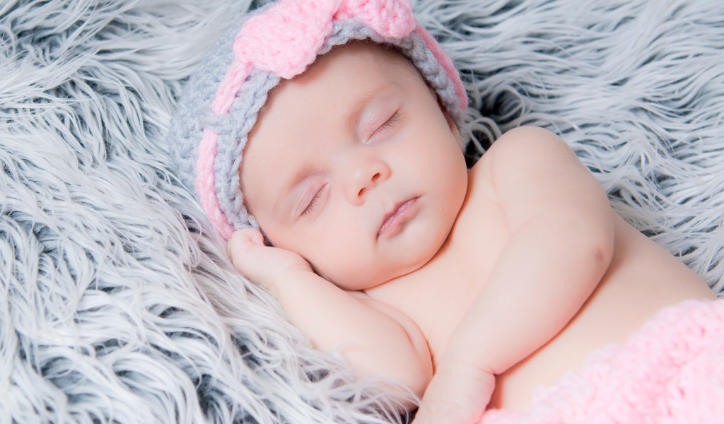 Грудной ребенок спит на меховом одеяле 