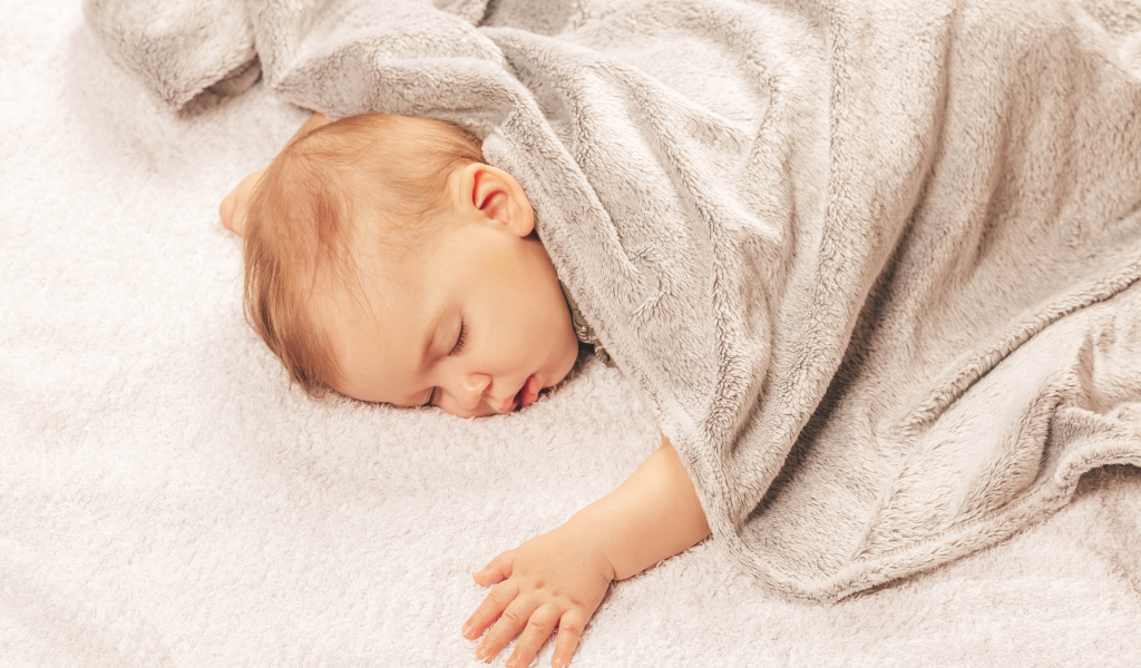 Грудной спящий ребенок под одеялом 