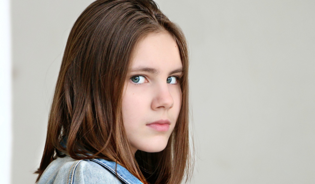 Красивая зеленоглазая девочка на сером фоне