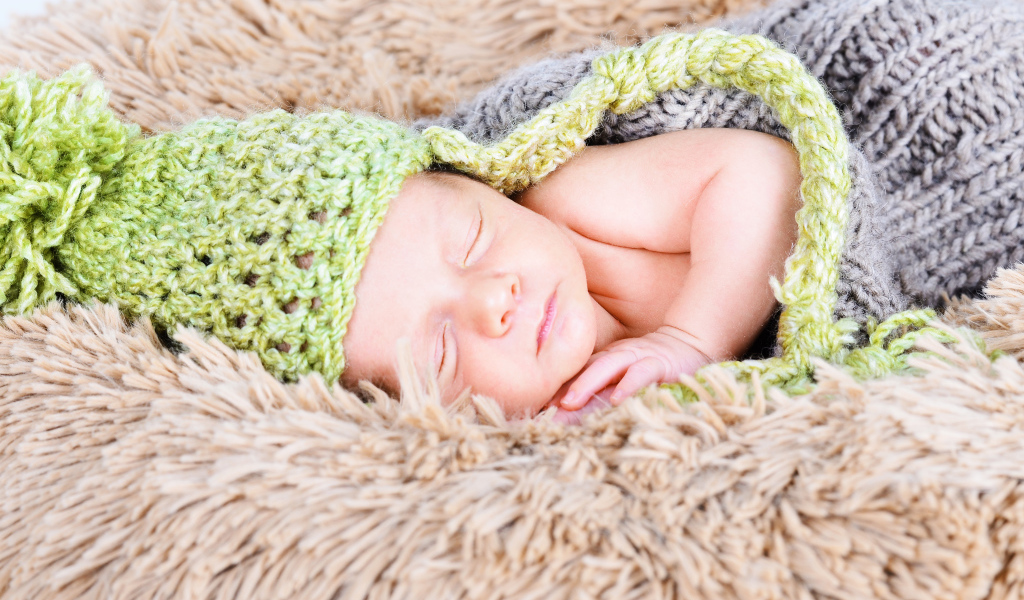 Красивый спящий грудной ребенок в вязаном костюме 