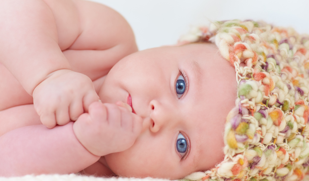 Голубоглазый грудной ребенок в шапке 