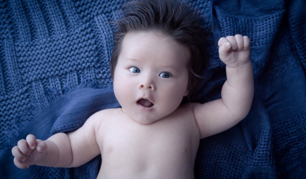 Мальчик с густыми волосами на синем покрывале 