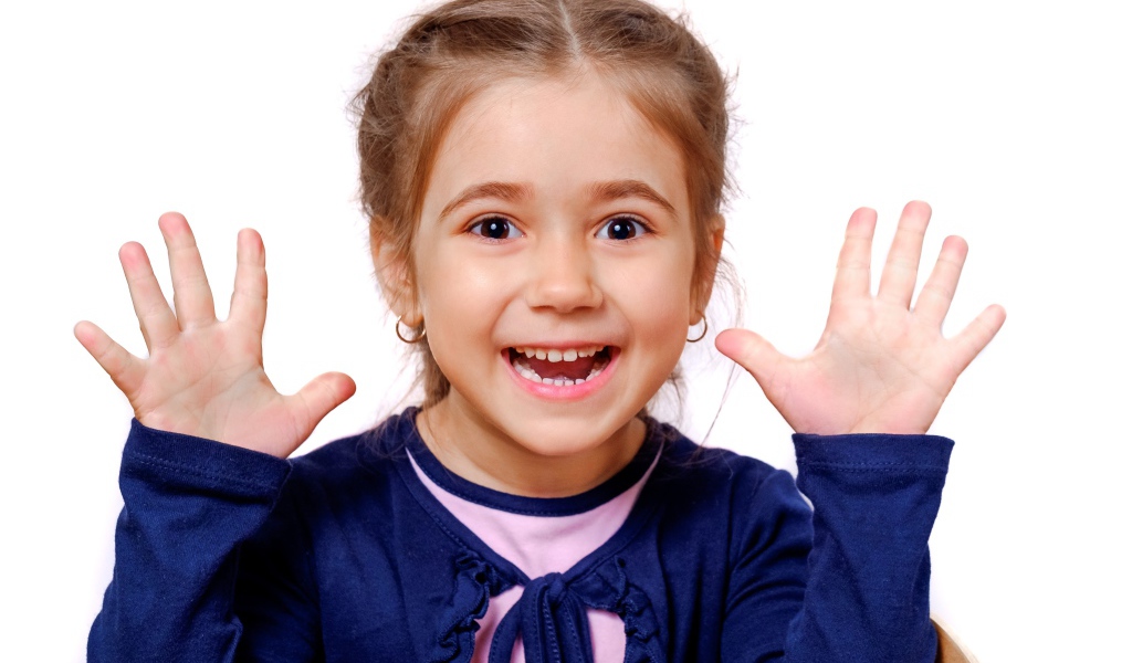 Веселая маленькая девочка с поднятыми руками