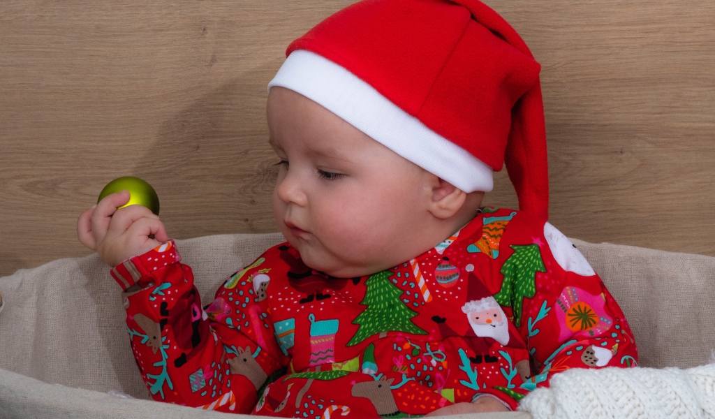 Ребенок в новогодней шапке с игрушкой в руке