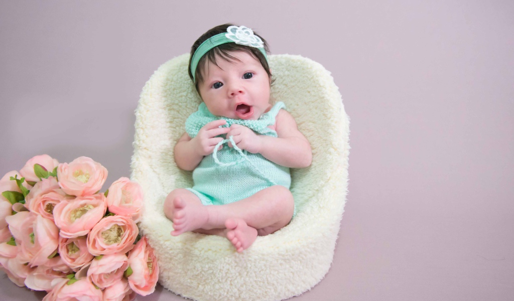 Милая малышка в кресле с букетом цветов