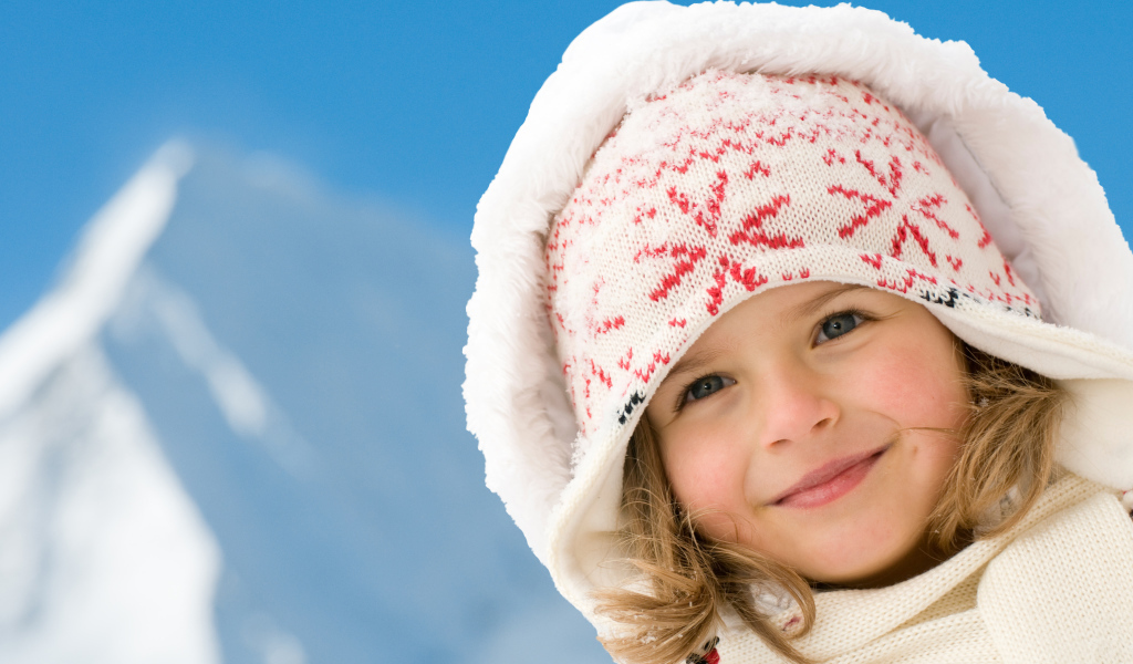 Милая маленькая девочка в шапке на фоне неба