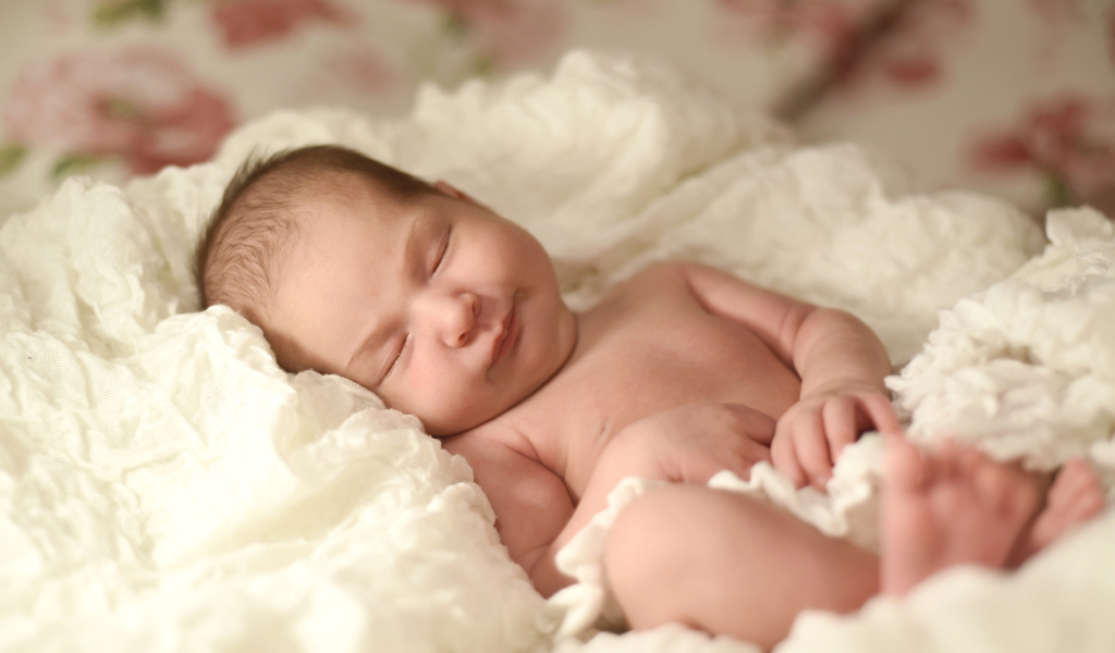 Милый грудной ребенок спит на белом покрывале 