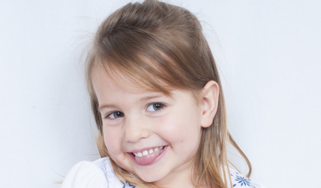 Милая улыбающаяся девочка с высунутым языком