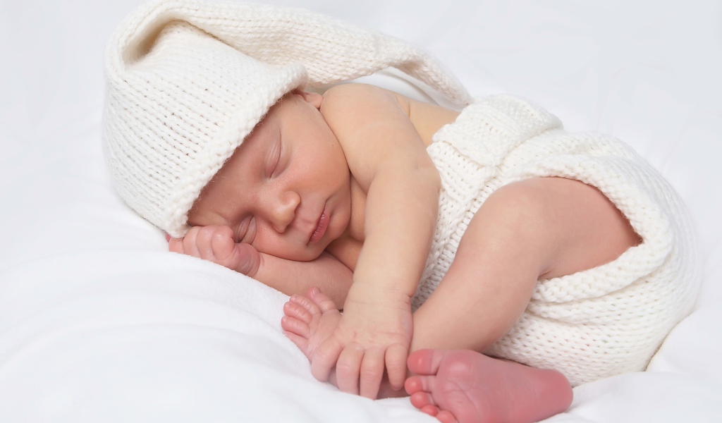 Нежный новорожденный ребенок в белом костюме