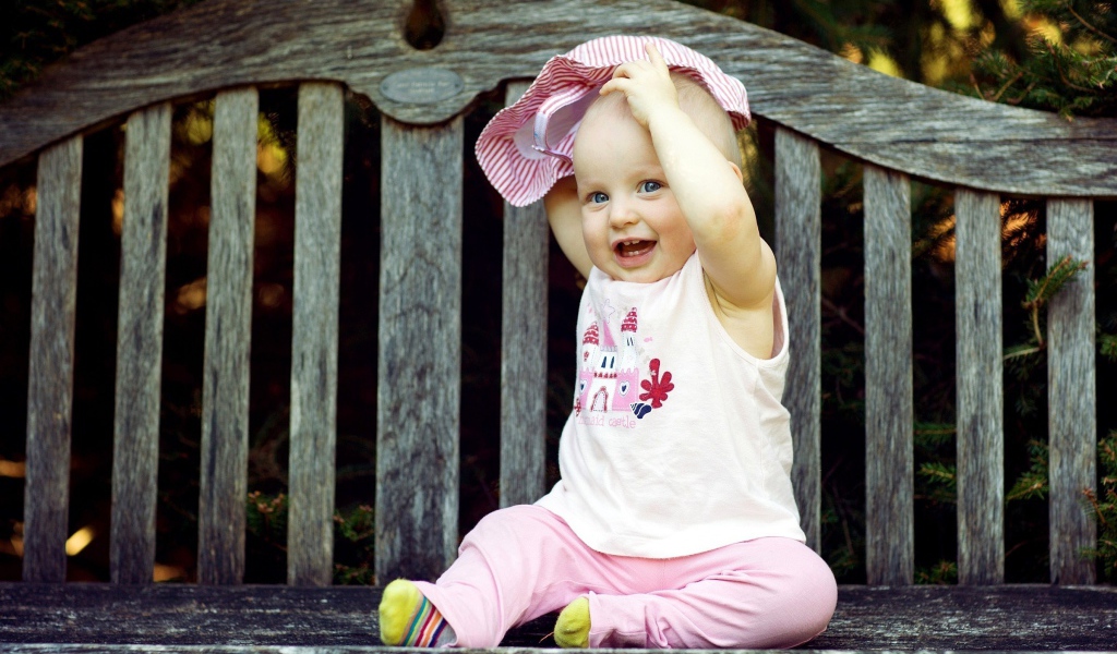 Смешной маленький ребенок сидит на лавке