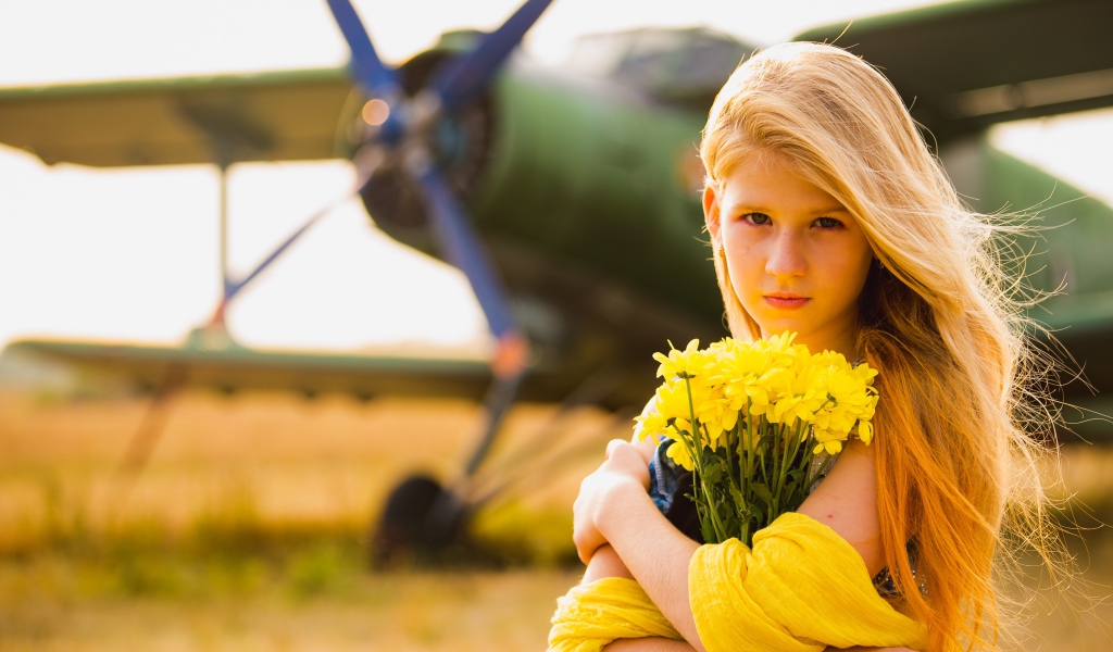 Девочка с букетом желтых хризантем у самолета 