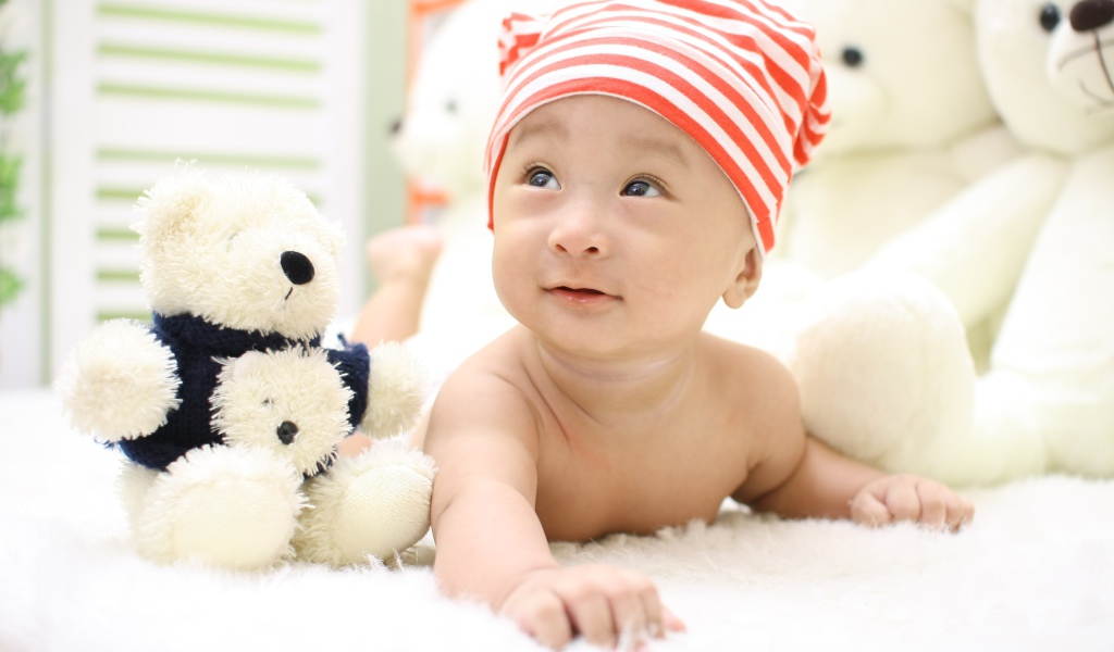 Маленький мальчик азиат на кровати с игрушкой