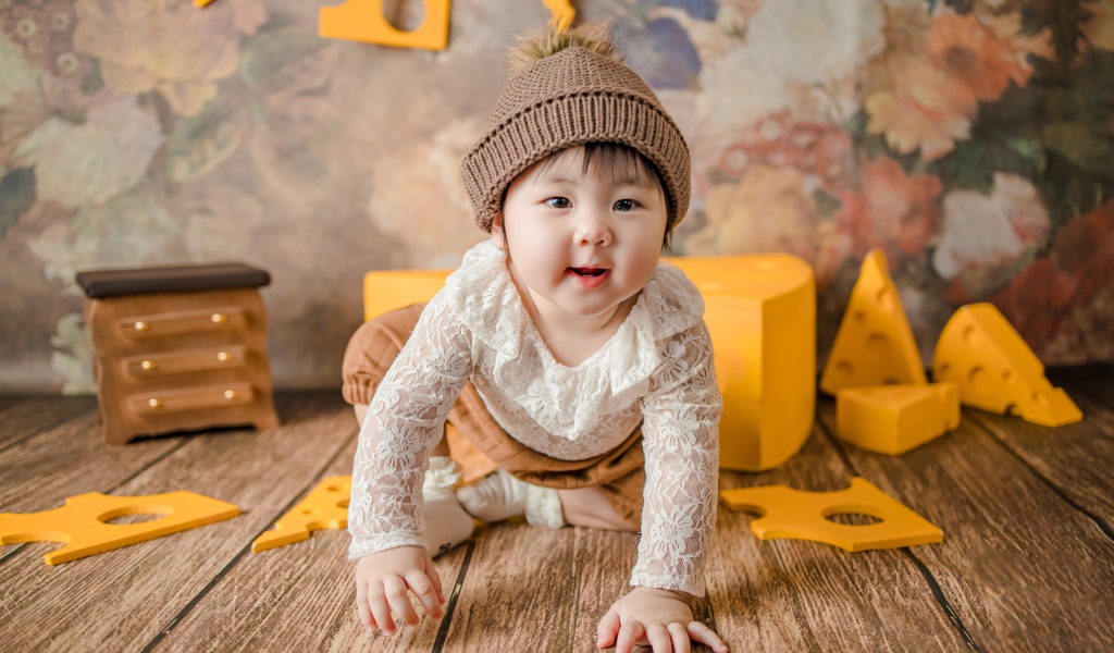 Маленький азиатский ребенок на полу с игрушками