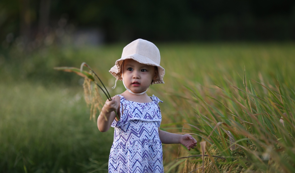 Маленькая девочка азиатка стоит в траве