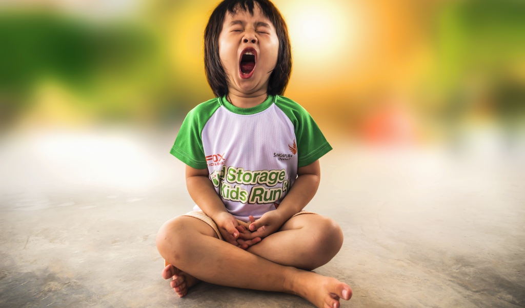 Маленькая девочка азиатка зевает на полу