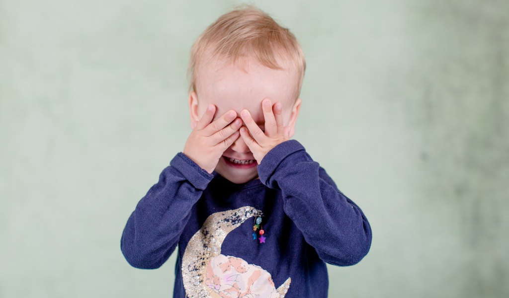 Маленький мальчик закрыл руками лицо 