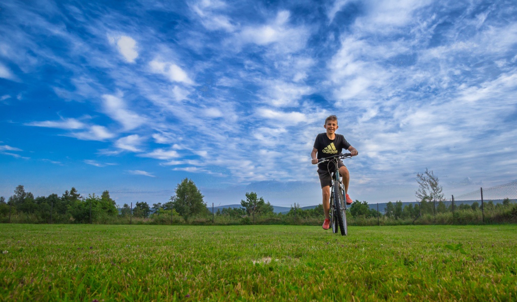 Маленький мальчик катается на велосипеде по полю 